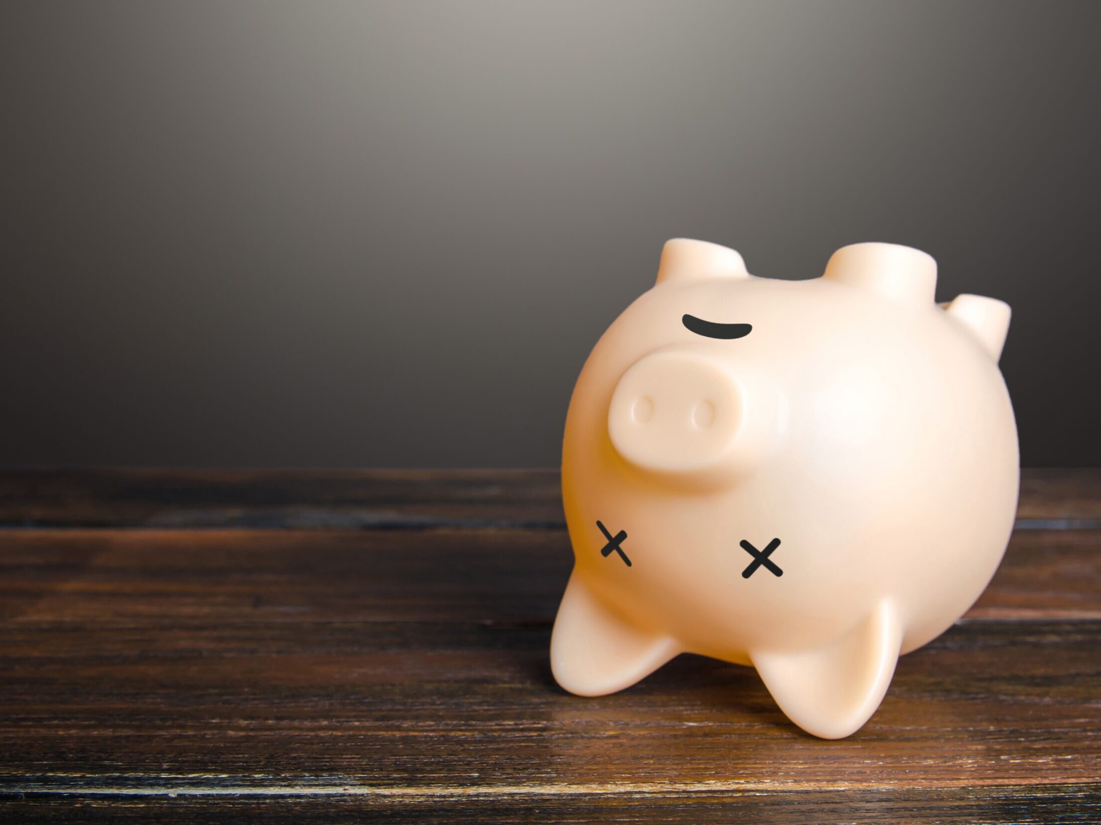 En sparegris med kryss som øyne ligger opp ned, som om den er død