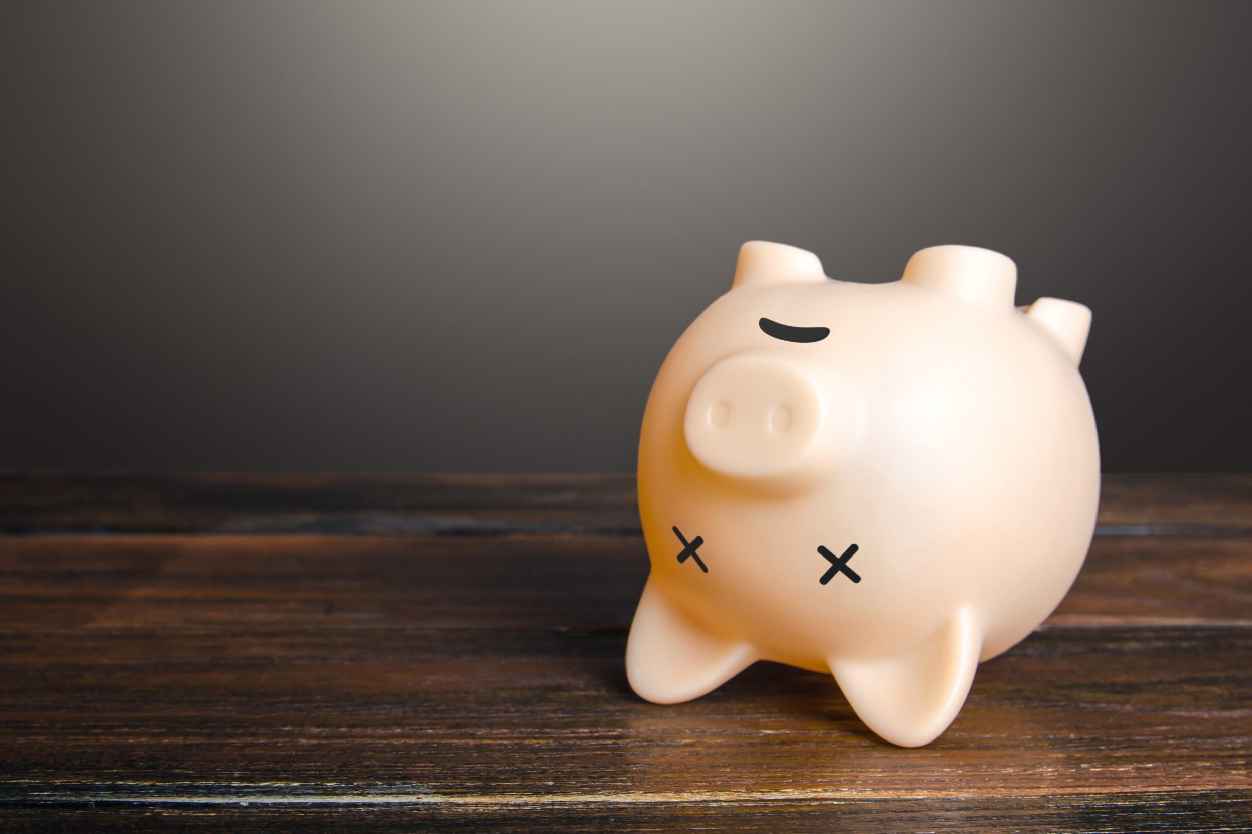 En sparegris med kryss som &oslash;yne ligger opp ned, som om den er d&oslash;d